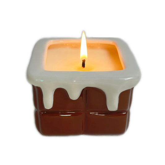 Chocolate ganache scented ceramic soy candle with a glossy drip-style design, lit and photographed on a white background.