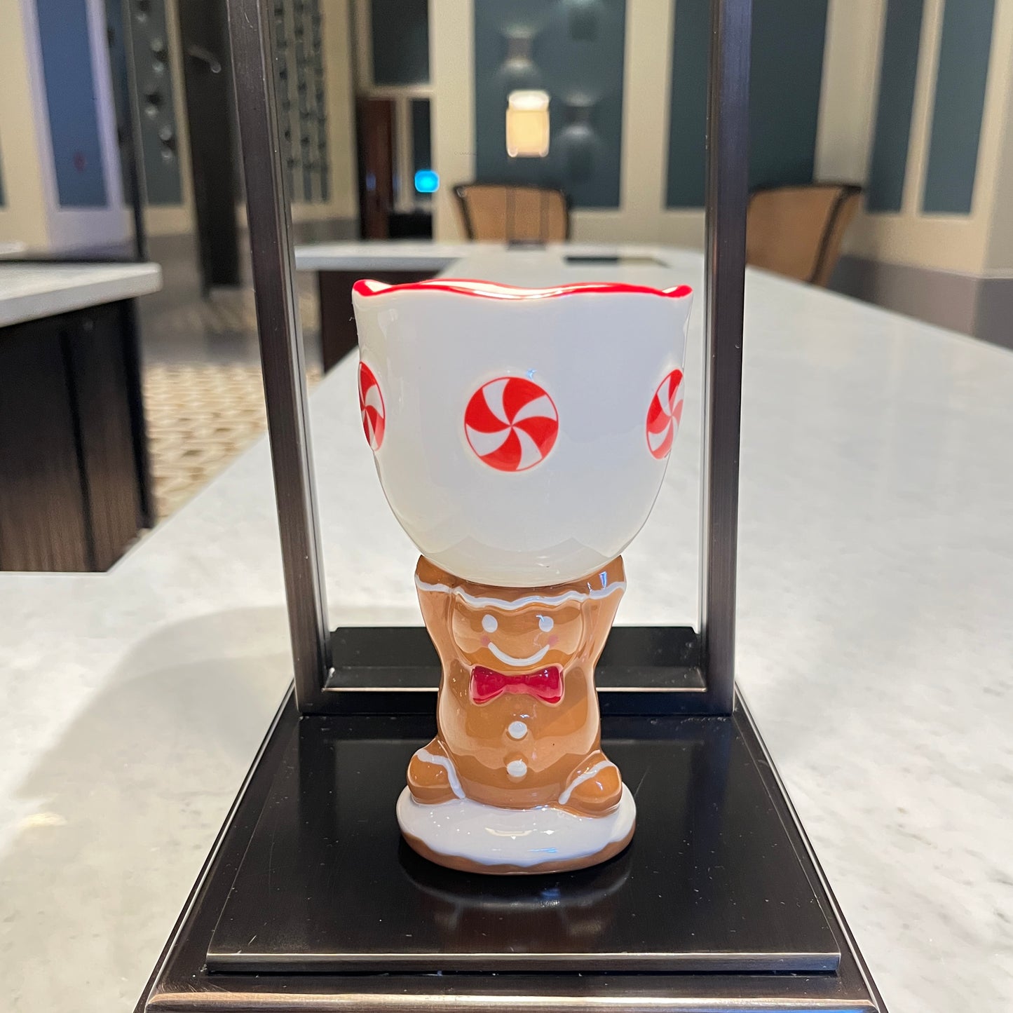 Gingerbread cookie scented ceramic gingerbread goblet candle with peppermint design displayed on a black tabletop stand.