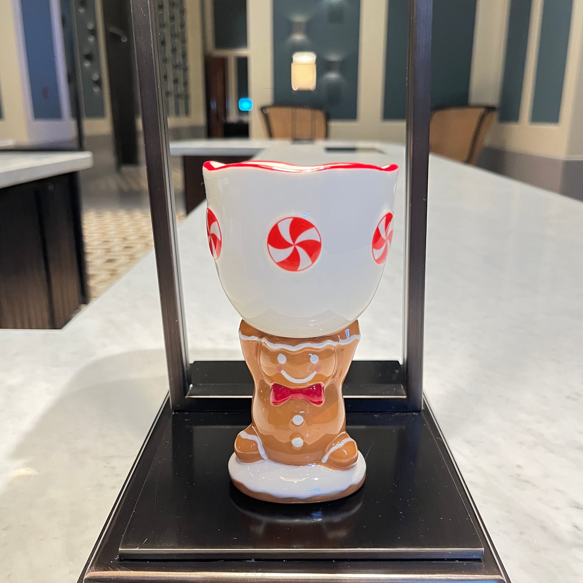 Gingerbread cookie scented ceramic gingerbread goblet candle with peppermint design displayed on a black tabletop stand.