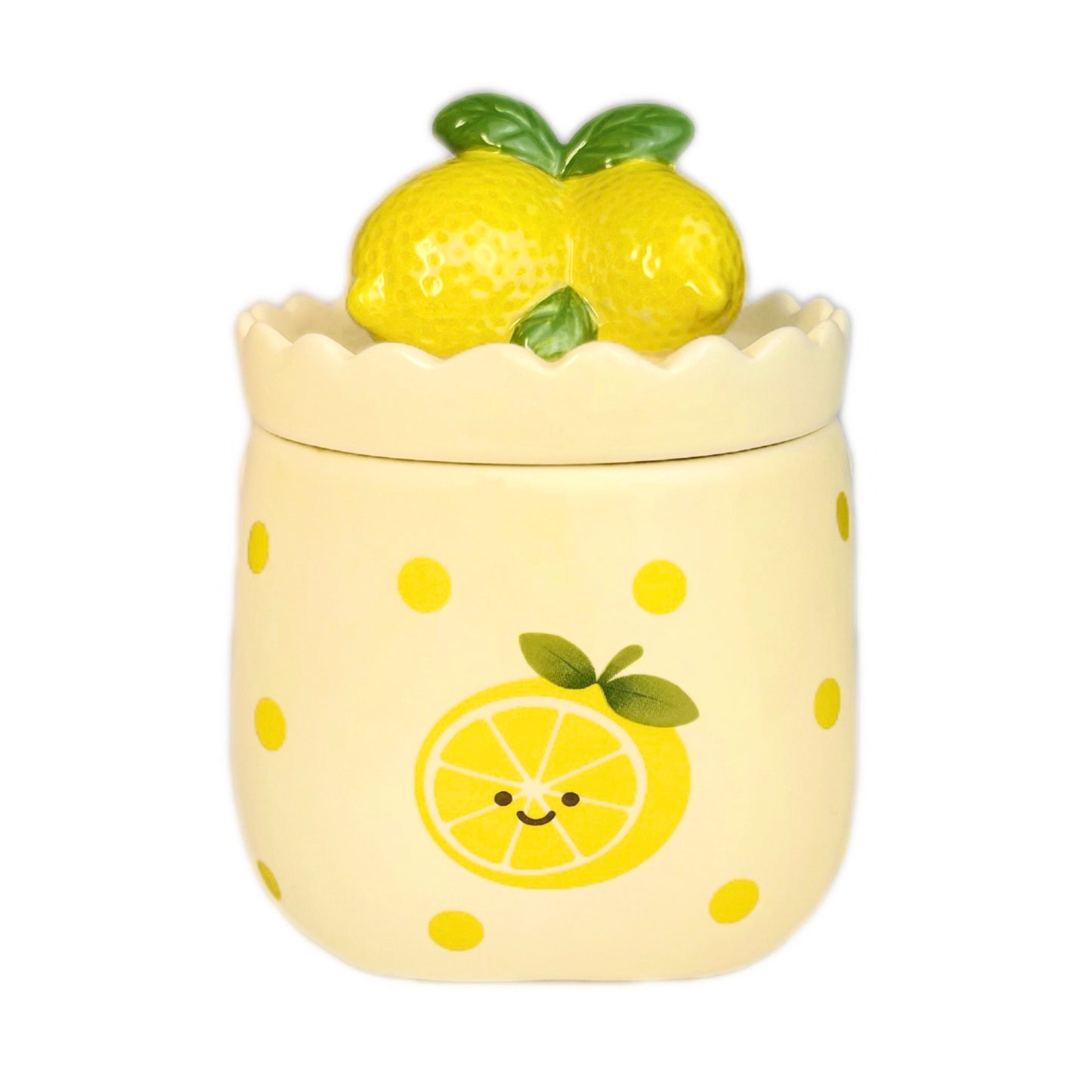 Sugared lemon zest scented candle in a cute ceramic jar with a scalloped rim, smiling lemon illustration on the front, and a lemon-shaped lid, photographed on a white background.
