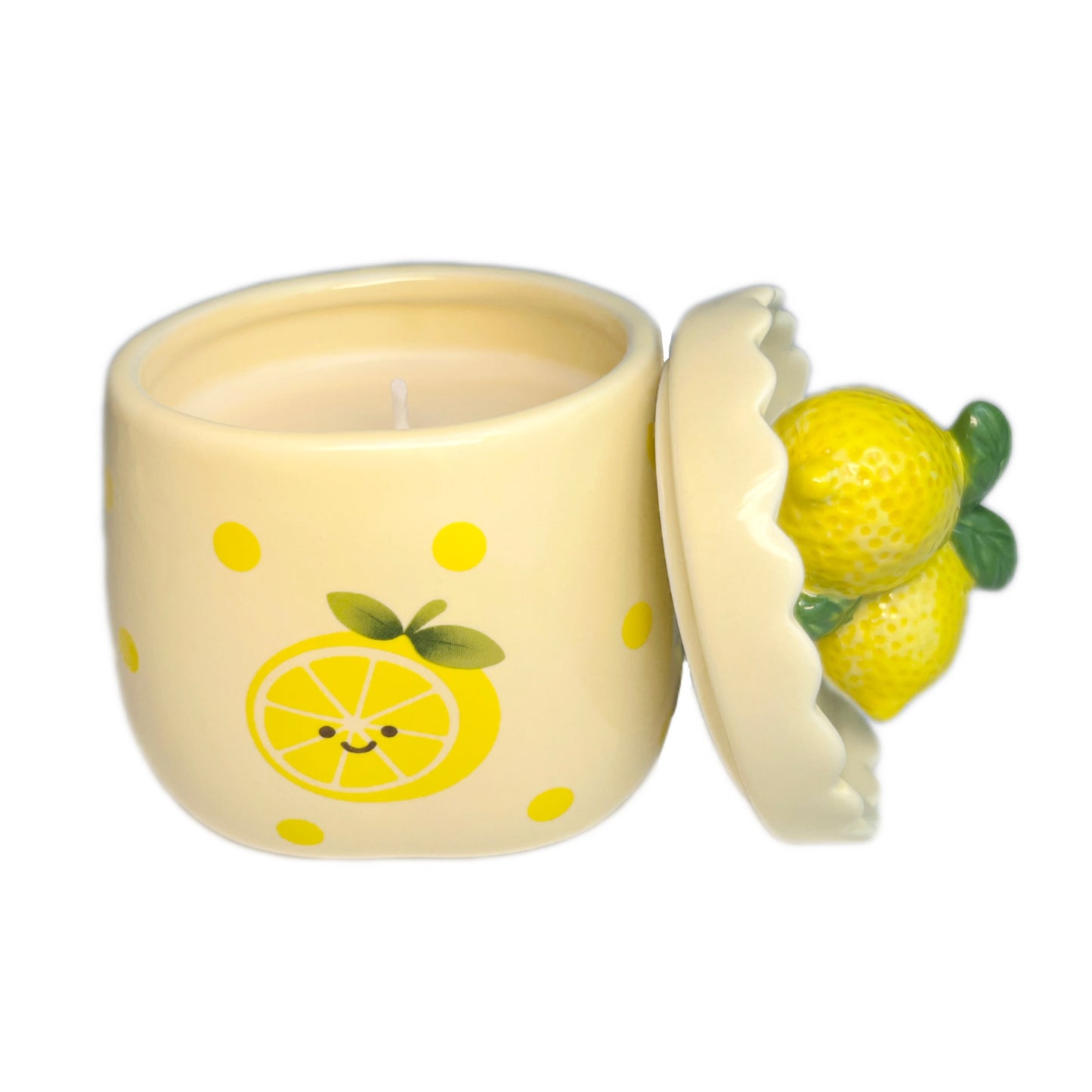 Sugared lemon zest scented candle in a ceramic jar with yellow polka dots and a smiling lemon illustration, shown open with the lemon-shaped lid resting beside it on a white background.