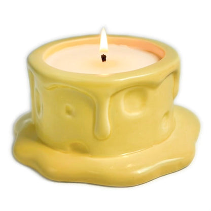 Vanilla cheesecake-scented ceramic soy candle designed like a cheese wheel with dripping glaze, photographed on a white background.