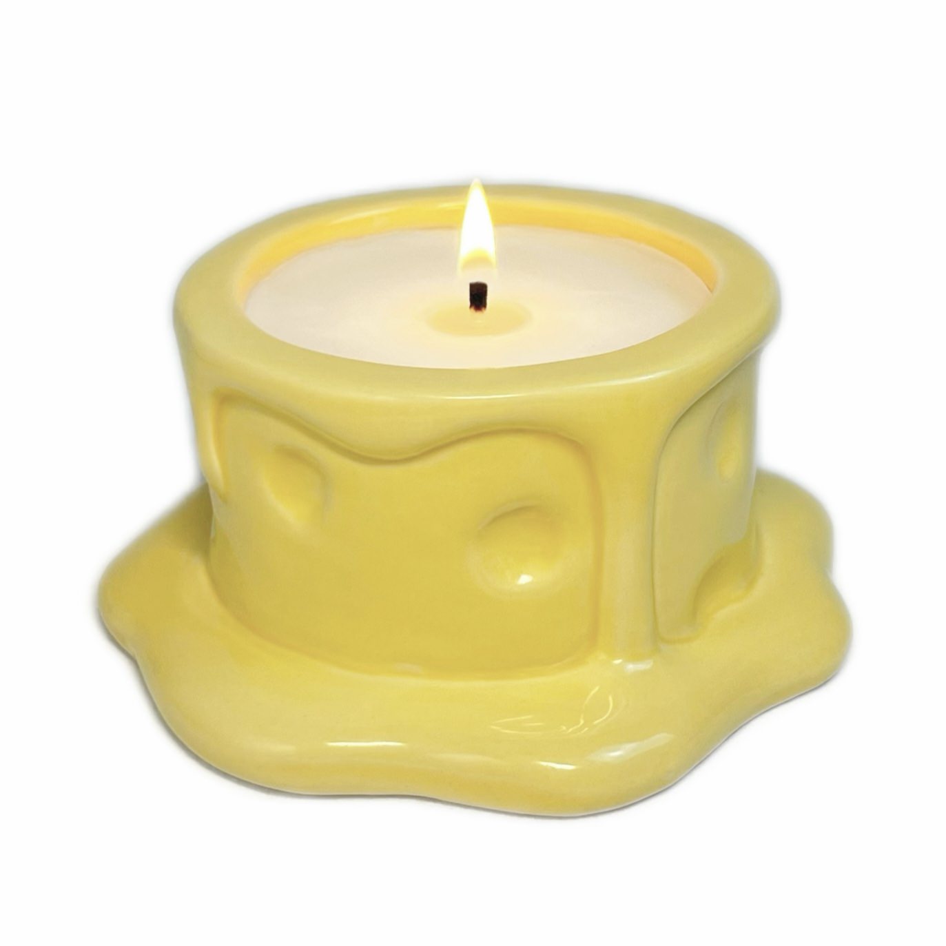 Vanilla cheesecake-scented ceramic soy candle designed like a cheese wheel with dripping glaze, photographed on a white background.